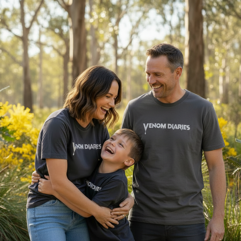 Family of three wearing 'Venom Diaries' shirts in a natural setting with trees and plants.